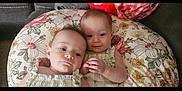 Kaiya And Delilah is registered to the contest to win money with this photo: baby, infant, twin, pillow, floral, couch, clothing, cute, portrait, child, toddler, resting, two_people, indoors, soft, skin, head, face, closeup, comfort