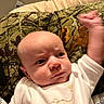 Thomas is registered to the contest to win money with this photo: baby, infant, face, expression, fist, camo_cushion, white_clothing, indoor, person, portrait, closeup, head, skin, cheek, eyes, nose, mouth, hand, furniture, couch