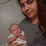 Thomas is registered to the contest to win money with this photo: baby, woman, holding, indoor, person, infant, face, skin, clothing, bed, blanket, hand, sitting, young, casual, portrait, curious, expression, domestic, soft_lighting