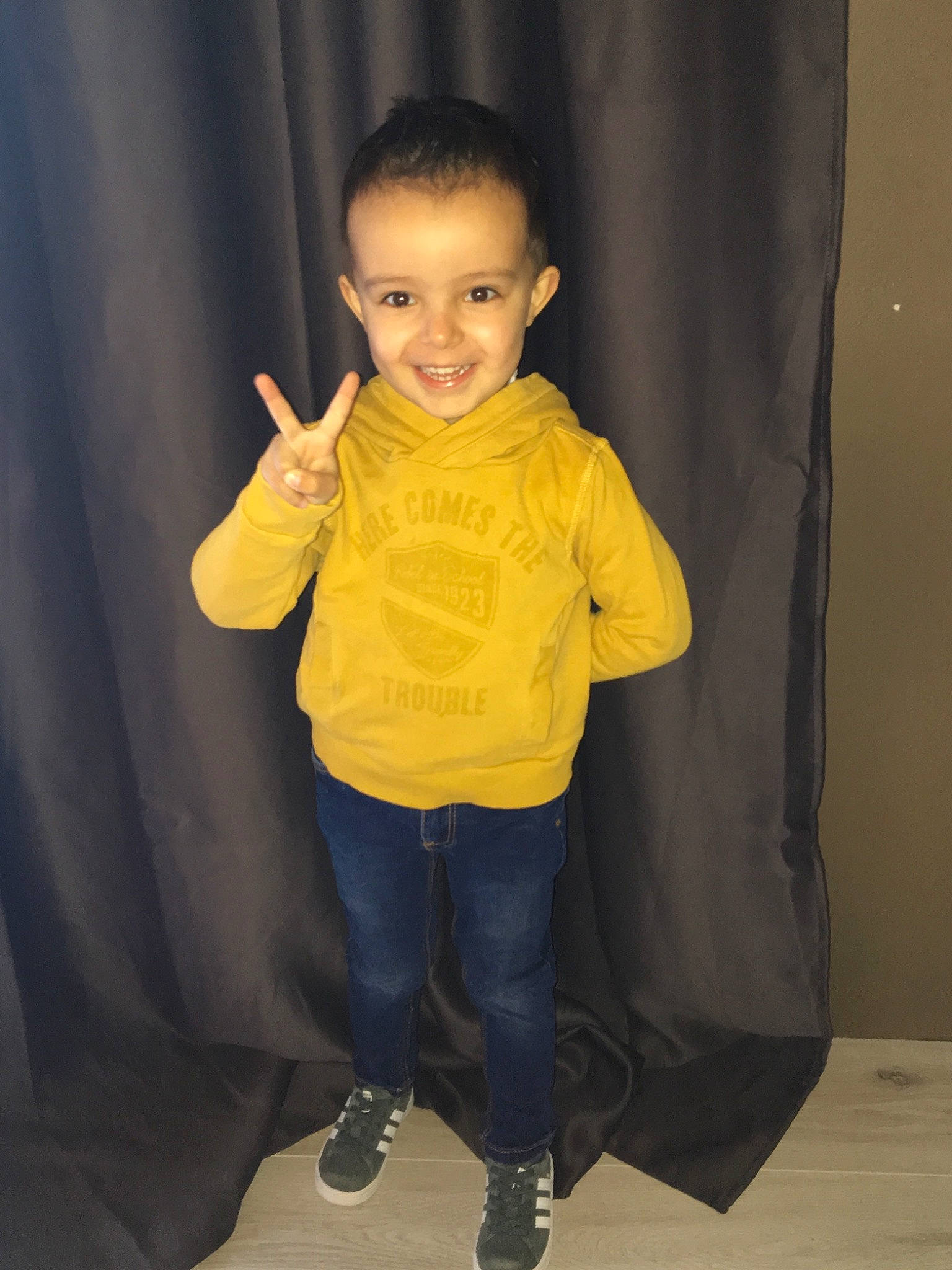 Gabin participe au concours pour gagner de l'argent avec cette photo : arm, child, child_model, fun, gesture, jacket, joy, outerwear, person, sleeve, smile, standing, toddler, yellow