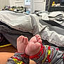 baby, feet, pajamas, car_pattern, bed, blanket, infant, cute, toes, sleepwear, soft, indoor, child, resting, clothing, comfort, playful, closeup, warm, relaxation