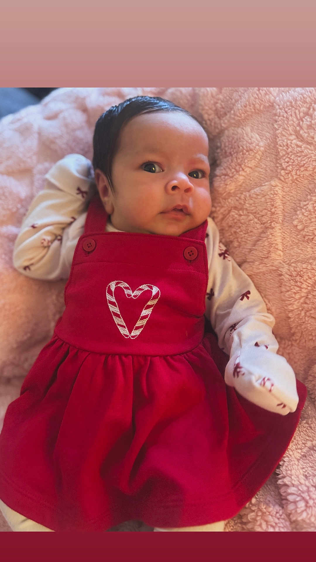 Milani is registered to the contest to win money with this photo: baby, blanket, candy_cane, clothing, cute, expression, face, festive, heart, holiday, indoors, infant, long_sleeves, lying_down, newborn, person, pink, portrait, red_dress, soft_texture