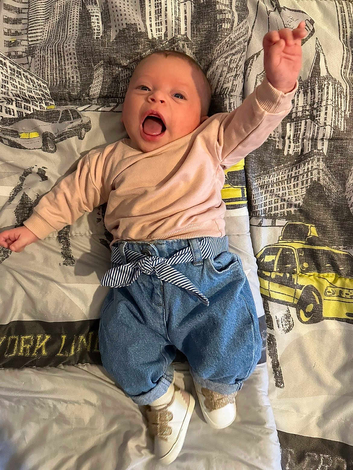 Alia participe au concours pour gagner de l'argent avec cette photo : baby, infant, smiling, happy, bed, bedding, blanket, jeans, sneakers, ribbon_belt, city_print, taxi, car, portrait, one_person, hand_raised, cute, mouth_open, newborn, indoor