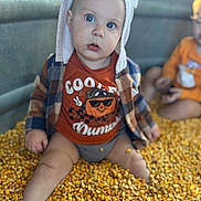 Kai joined the competition — help win amazing prizes! baby, child, hat, ears, plaid_jacket, orange_shirt, corn_kernels, sitting, indoor, curious, face, blue_eyes, clothing, autumn, playful, person, portrait, blurred_background, cute, toddler