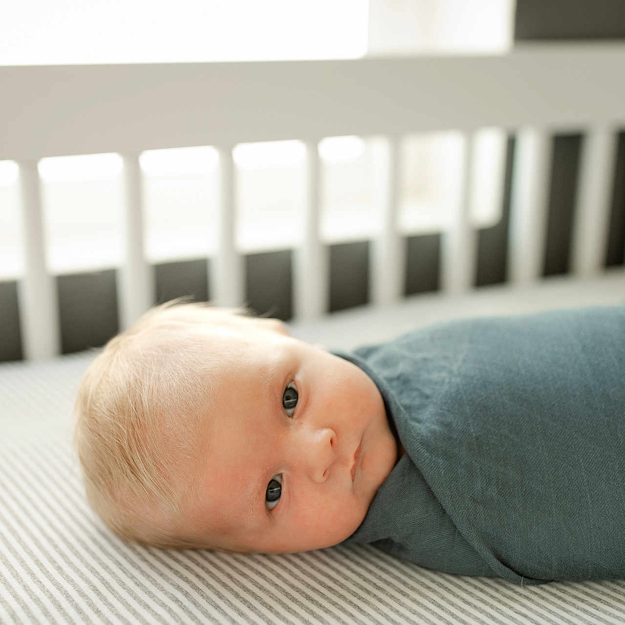 James is registered to the contest to win money with this photo: baby, bed, blanket, clothing, crib, cushion, face, furniture, happy, head, homedecor, indoors, infantbed, longsleeve, newborn, pants, person, photography, portrait, sleeve
