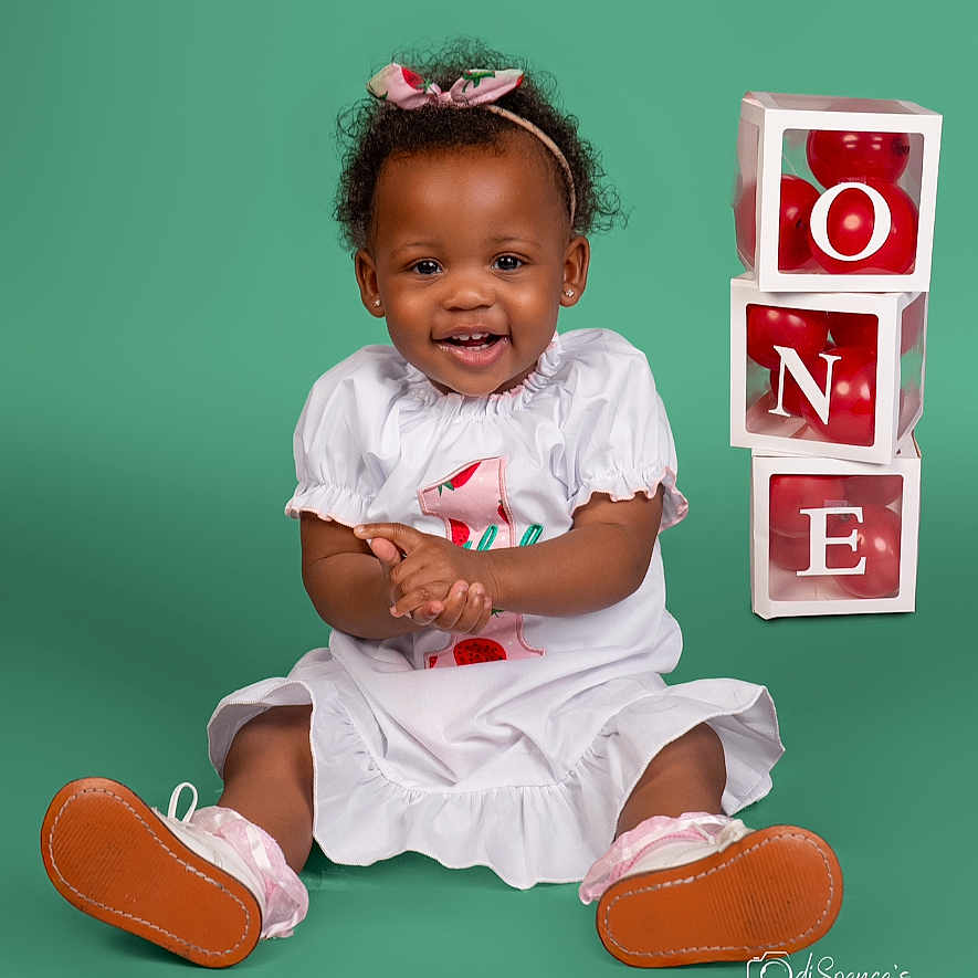 Kinslee is registered to the contest to win money with this photo: advertisement, bodypart, child, clothing, dress, face, female, finger, footwear, girl, hand, happy, head, person, photography, portrait, sandal, shoe, sitting, sneaker