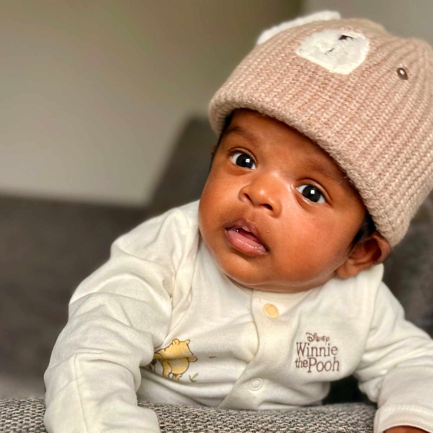 Aadhav joined the competition — help win amazing prizes! baby, bear_hat, child, clothing, couch, curious, cute, expression, eyes, face, furniture, indoor, infant, knitted_hat, mouth, onesie, portrait, soft_lighting, winnie_the_pooh, young_child