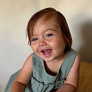 Emy participe au concours pour gagner de l'argent avec cette photo : toddler, child, smiling, portrait, blue_eyes, dress, short_hair, indoor, wooden_table, happy, cute, baby, skin, face, person, young_child, candid, expression, closeup, natural_light