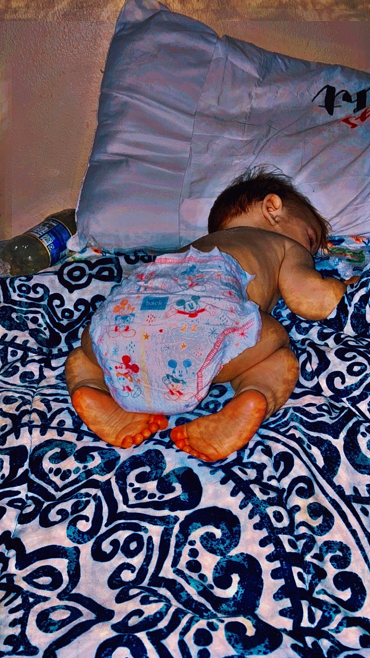 Clark is registered to the contest to win money with this photo: art, azure, baby, baby_toddler_clothing, bed_sheet, bedding, bedtime, child, comfort, design, flooring, linens, nap, pattern, person, purple, room, sitting, t_shirt, textile