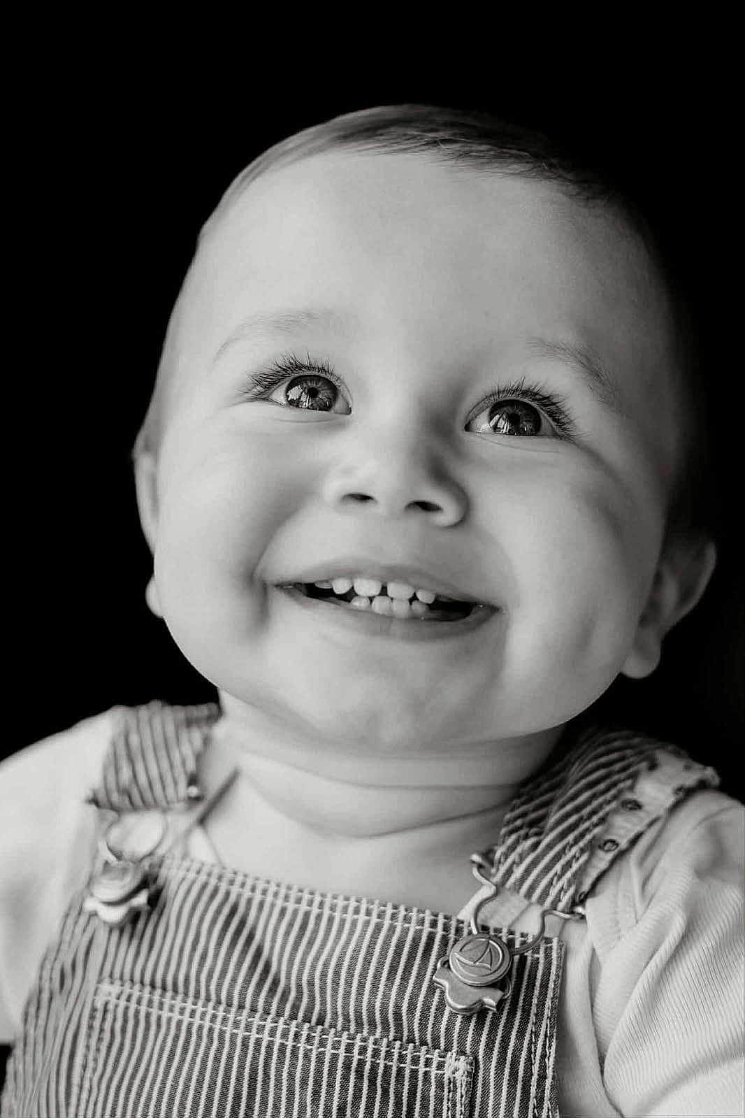 Malo participe au concours pour gagner de l'argent avec cette photo : baby, infant, child, smile, teeth, dimples, eyes, eyelashes, gaze_up, portrait, close_up, high_contrast, monochrome, black_background, overalls, striped_overalls, clothing, happy, studio_portrait, candid