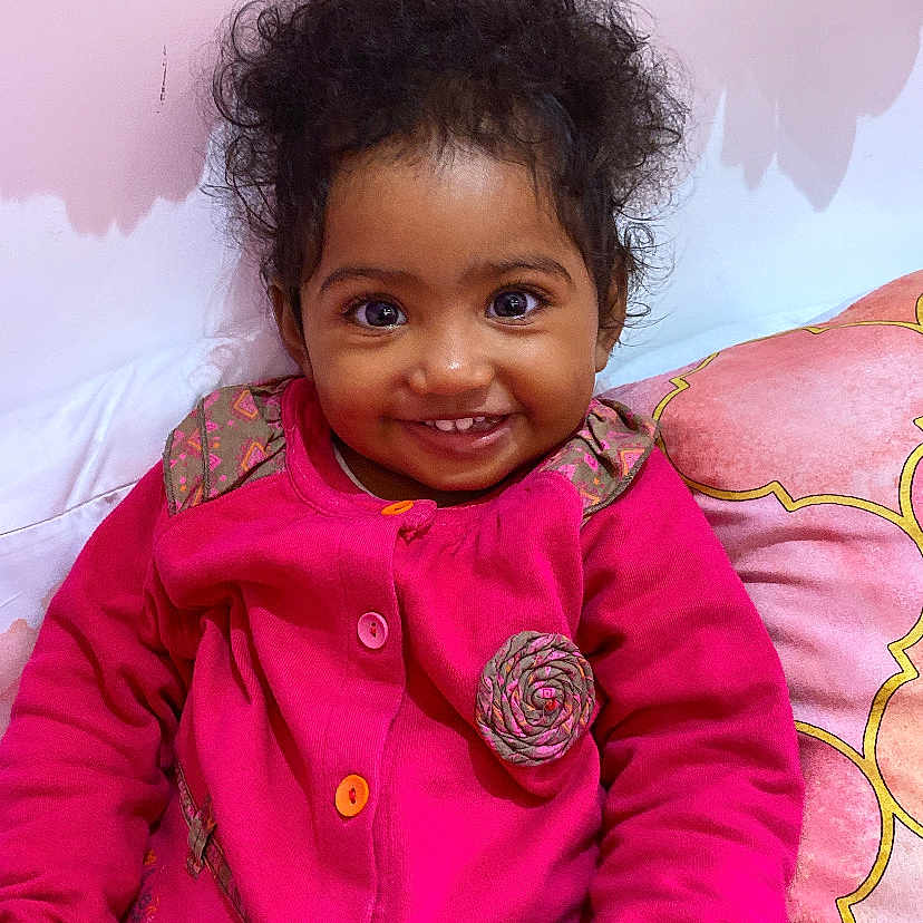 Mayanah participe au concours pour gagner de l'argent avec cette photo : bright_colors, child, closeup, cozy, crayon, cup, curly_hair, cushion, cute, face, floral_decor, happy, holding, indoor, pink_jacket, portrait, seated, smiling, toddler, young