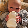 Albie-Paul joined the competition — help win amazing prizes! baby, bottle, milk, hand, couch, blanket, striped_clothing, face, infant, smile, happy, indoor, person, holding, closeup, child, cozy, furniture, comfort, feeding