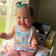 Astrid joined the competition — help win amazing prizes! child, curtains, cushion, hair_bow, happy, home, indoor, patterned_fabric, person, pink_pants, portrait, scissors, sitting, smiling, storage_bin, sunlight, toddler, vinyl_gloves_box, white_tank_top, window