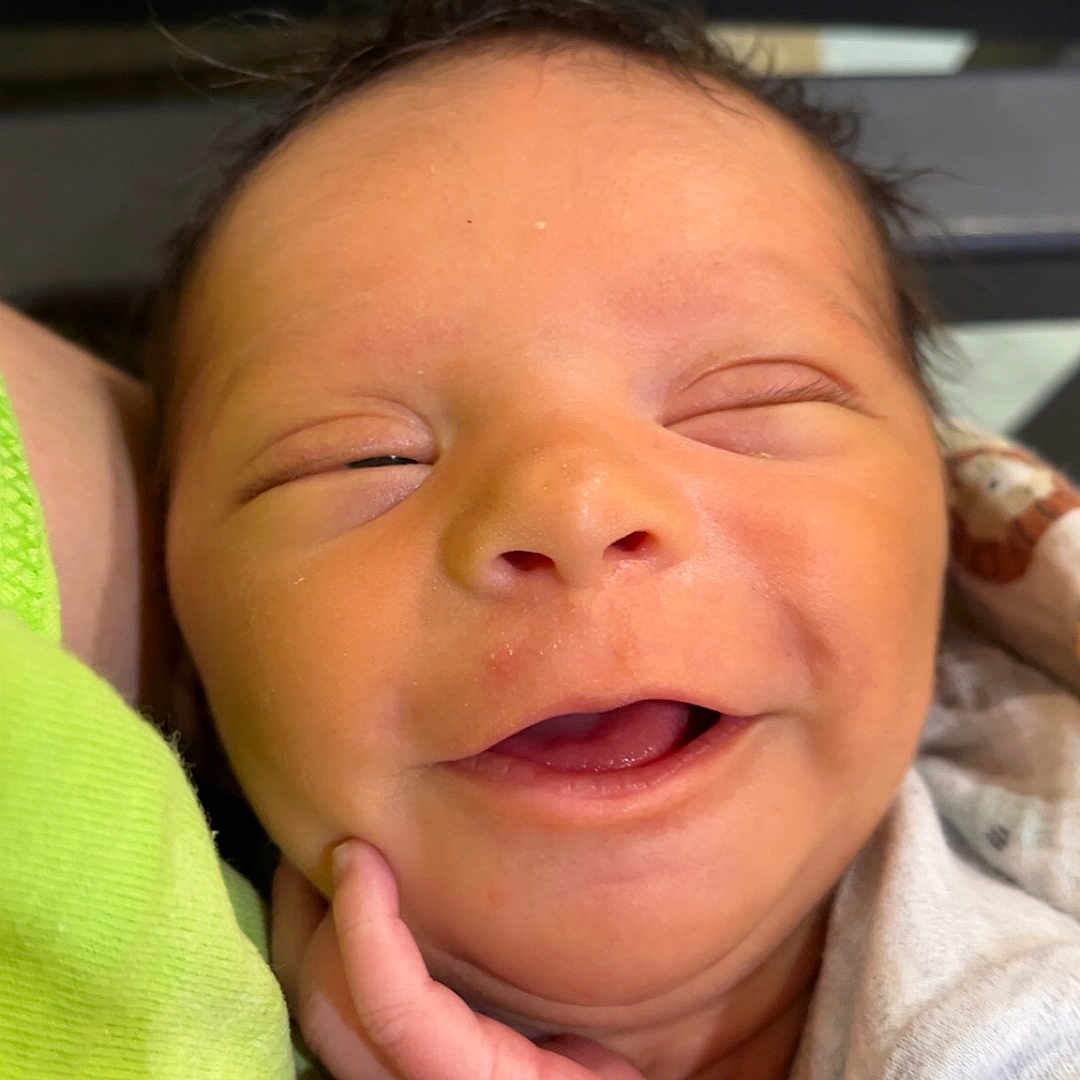 Kingston is registered to the contest to win money with this photo: newborn, baby, smile, face, hand, infant, close_up, skin, eyes_closed, clothing, peaceful, cute, person, portrait, young_child, happy, resting, soft, indoors, human