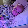 Ryder is registered to the contest to win money with this photo: baby, hospital, bed, blanket, medical_tube, medical_patch, face, child, pajamas, pillow, purple_light, infant, healthcare, patient, cute, indoors, young_child, lying_down, comfort, hospital_room