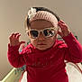 Séréna participe au concours pour gagner de l'argent avec cette photo : accessory, baby, blanket, changing_table, child, cute, eyewear, flower_accessory, hands, headband, indoor, infant, pants, pink_headband, playful, portrait, red_shirt, seated, sunglasses, toddler