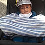 baby, child, stroller, blanket, hat, panda, face, outdoor, curious, clothing, infant, cute, portrait, young_child, seat, warm, striped_blanket, baby_boy, headwear, daylight