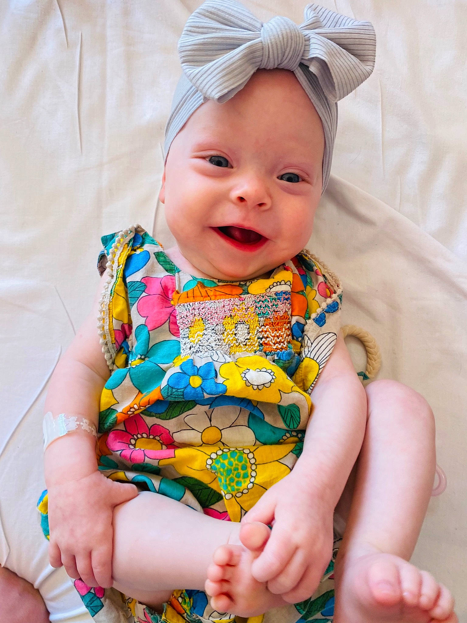 Aila is registered to the contest to win money with this photo: baby, baby_toddler_clothing, child, dress, eye, face, fashion_accessory, happy, head, headband, headpiece, headwear, pattern, peach, person, pink, product, sitting, skin, sleeve