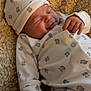 Reuben is registered to the contest to win money with this photo: baby, infant, sleeping, smiling, hat, onesie, bear_pattern, blanket, soft_texture, cute, cozy, child, newborn, resting, hand, clothing, portrait, indoors, warm, peaceful