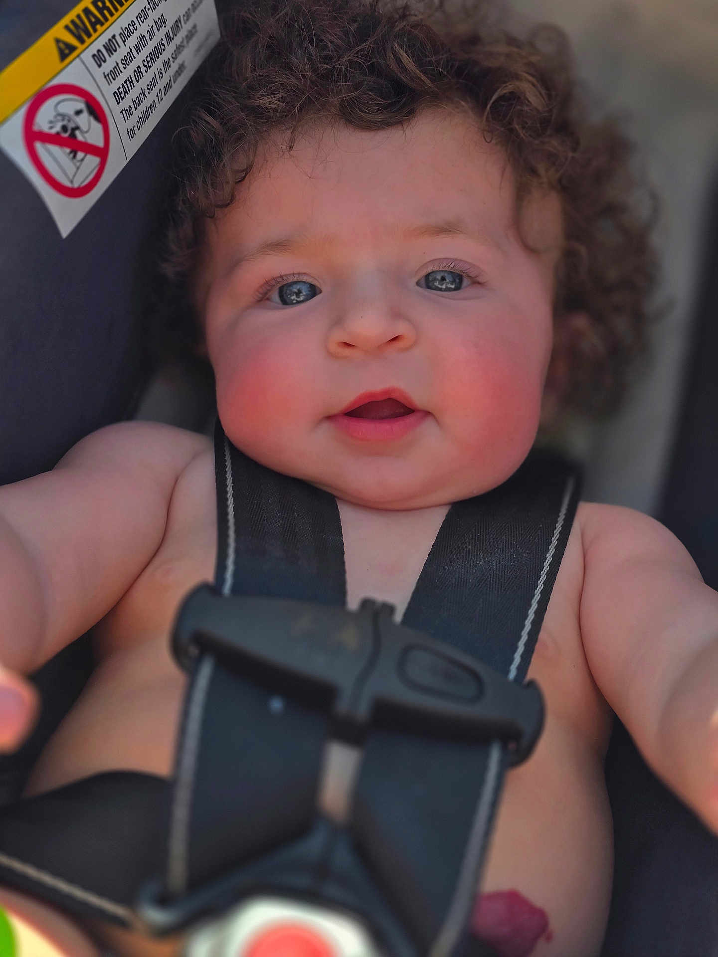 Lilith joined the competition — help win amazing prizes! baby, child, car_seat, curly_hair, face, blue_eyes, rosy_cheeks, seatbelt, safety, infant, closeup, skin, expression, cute, young, person, warning_label, car_safety, seat_strap, portrait