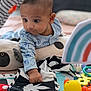 baby, child, toy, rubber_duck, play_mat, onesie, animal_prints, curious, infant, soft_toys, colorful, indoor, cute, hand, face, expression, pillow, striped, black_and_white, playtime