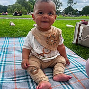 Ezra joined the competition — help win amazing prizes! baby, child, smiling, sitting, blanket, park, grass, outdoor, bib, pants, lion_design, footwear, people, trees, sky, clouds, bag, playground, daytime, cute