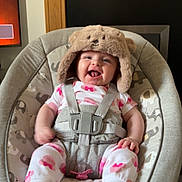 Emily is registered to the contest to win money with this photo: baby, infant, smiling, hat, bear_hat, pajamas, baby_seat, elephant_pattern, cushion, happy, tongue_out, home_interior, wooden_mantle, framed_photos, feet, child, indoors, cute, baby_accessory, seatbelt