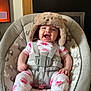baby, infant, smiling, hat, bear_hat, pajamas, baby_seat, elephant_pattern, cushion, happy, tongue_out, home_interior, wooden_mantle, framed_photos, feet, child, indoors, cute, baby_accessory, seatbelt