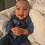 Omari-Momodou is registered to the contest to win money with this photo: baby, child, infant, smiling, clapping, onesie, blue_clothing, blanket, quilt, indoor, cozy, happy, cute, portrait, hands, face, seated, soft_lighting, home, toddler