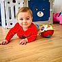 baby, child, crawling, red_shirt, wooden_floor, toy_ball, pink_unicorn_toy, blue_bear_playpen, indoor, play_area, flooring, cute, smiling, person, infant, colorful, playtime, young_child, home, fun
