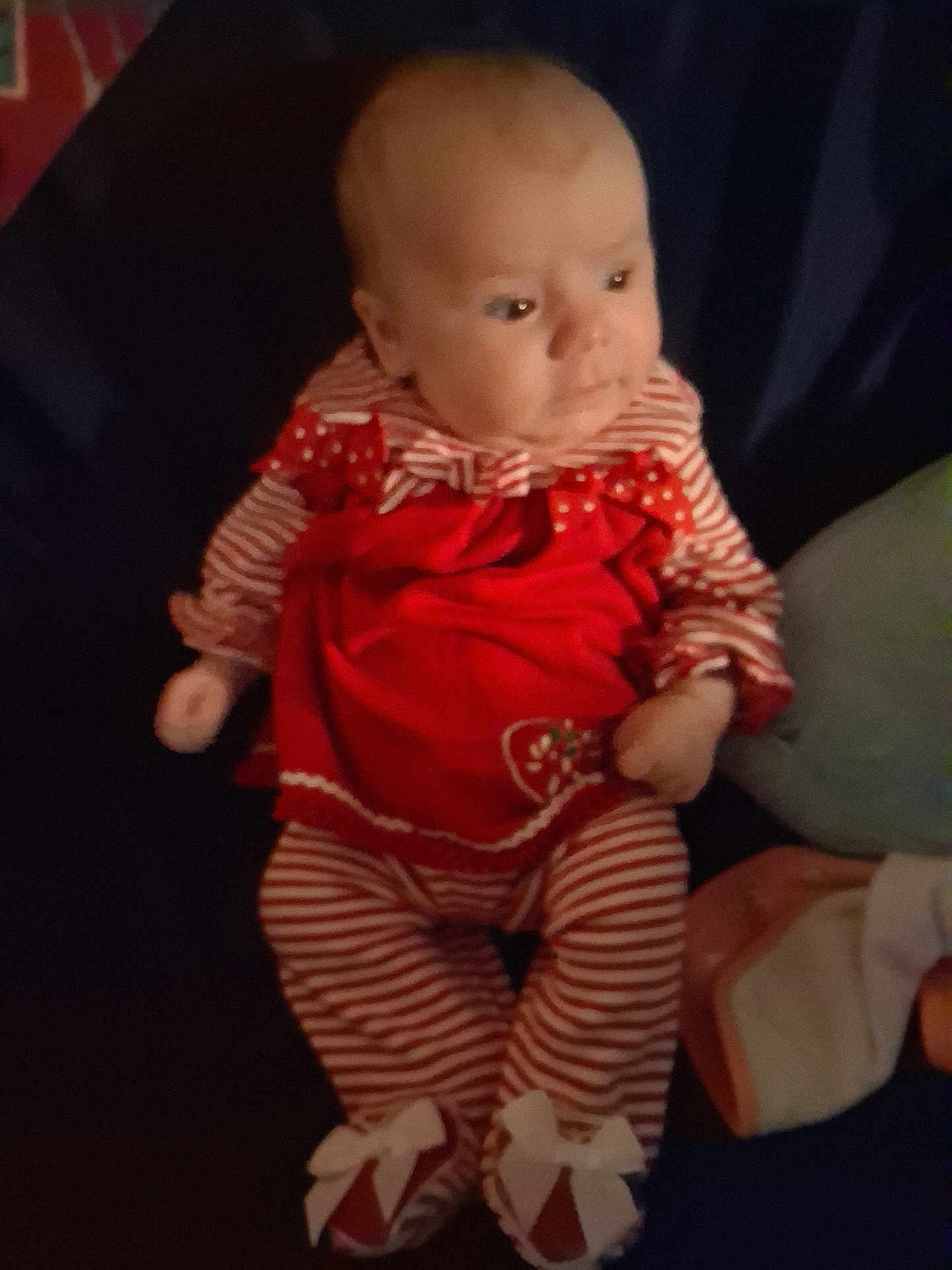 Macy is registered to the contest to win money with this photo: baby, infant, red_clothing, striped_clothing, footwear, bow, cute, child, portrait, indoors, soft_lighting, sitting, small_hands, face, head, young_child, cozy, comfort, holiday_outfit, relaxed