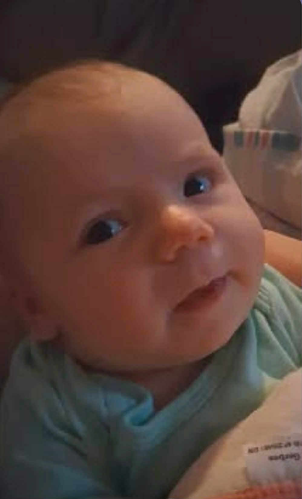 Macy joined the competition — help win amazing prizes! baby, infant, face, close_up, blue_clothing, smile, curious_eyes, soft_light, blanket, indoors, cute, child, young, portrait, head, skin, human, resting, comfort, warm