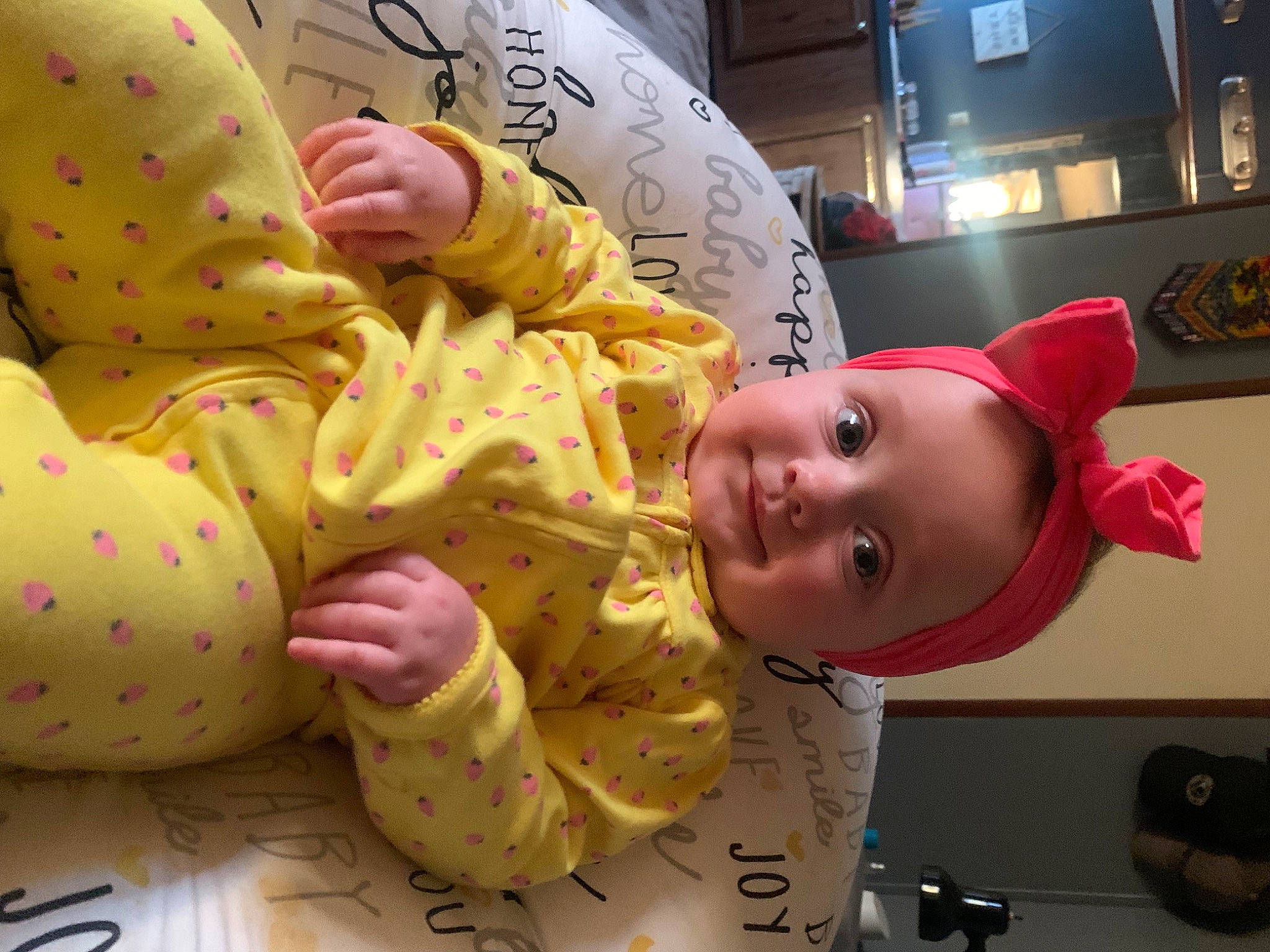 Harper is registered to the contest to win money with this photo: baby, baby_toddler_clothing, cheek, child, comfort, facial_expression, finger, fun, happy, human_body, joy, linens, nose, person, photograph, product, room, skin, smile, snapshot