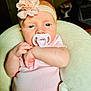 Ryleigh is registered to the contest to win money with this photo: baby, infant, pacifier, headband, flower, pink_clothing, onesie, plush_pillow, indoor, close_up, skin, hand, face, blue_eyes, cute, comfort, newborn, child, baby_girl, soft_texture