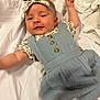 baby, blanket, blue_dress, buttons, child, cozy, cute, fabric, floral_pattern, happy, headband, indoors, infant, lying_down, portrait, raised_arms, smiling, soft_texture, white_bedspread, young_child