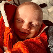Owen a rejoint le concours — aidez-le/la à gagner de superbes lots ! baby, smiling, orange_jacket, fleece, cozy, close_up, face, infant, child, sunlight, shadow, warm, happy, portrait, indoor, cute, soft_texture, clothing, newborn, peaceful