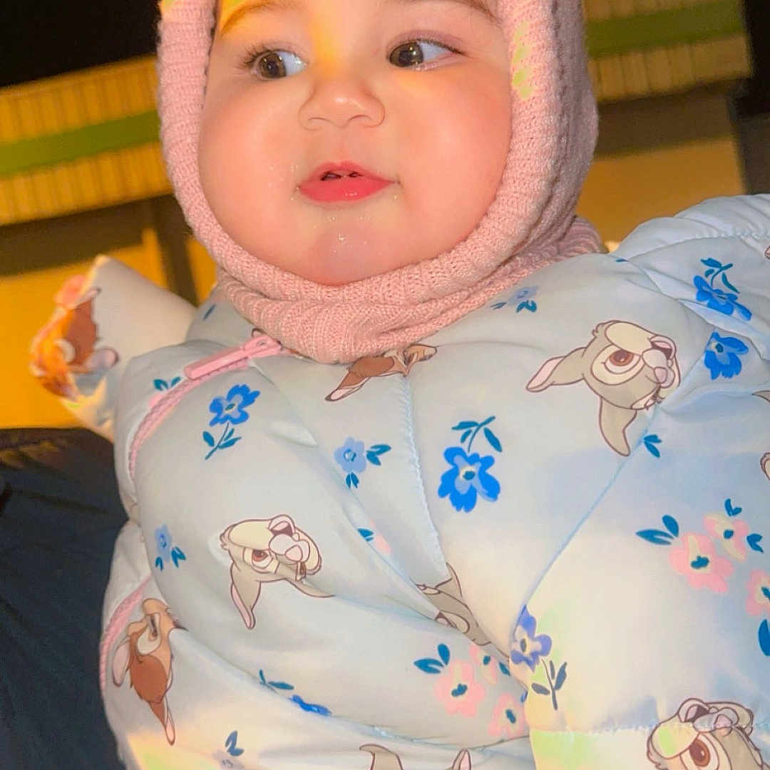 Elyn a rejoint le concours — aidez-le/la à gagner de superbes lots ! baby, blue, cartoon_print, child, cute, face, hand, holding, infant, jacket, knit_hat, night, outdoor, person, pink, pom_poms, portrait, smile, warm, winter_clothing