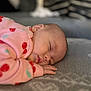baby, sleeping, pink_clothing, cherry_pattern, blanket, soft_texture, closeup, face, hand, cozy, indoor, child, peaceful, infant, portrait, cute, relaxing, rest, homedecor, toddler