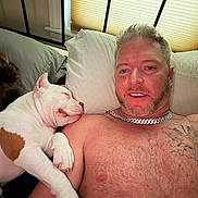 Ozzie joined the competition — help win amazing prizes! man, dog, bed, pillow, tattoo, shirtless, sleeping, resting, indoor, window, chain_necklace, pet, human, animal, comfort, relaxation, closeup, friendship, casual, hair