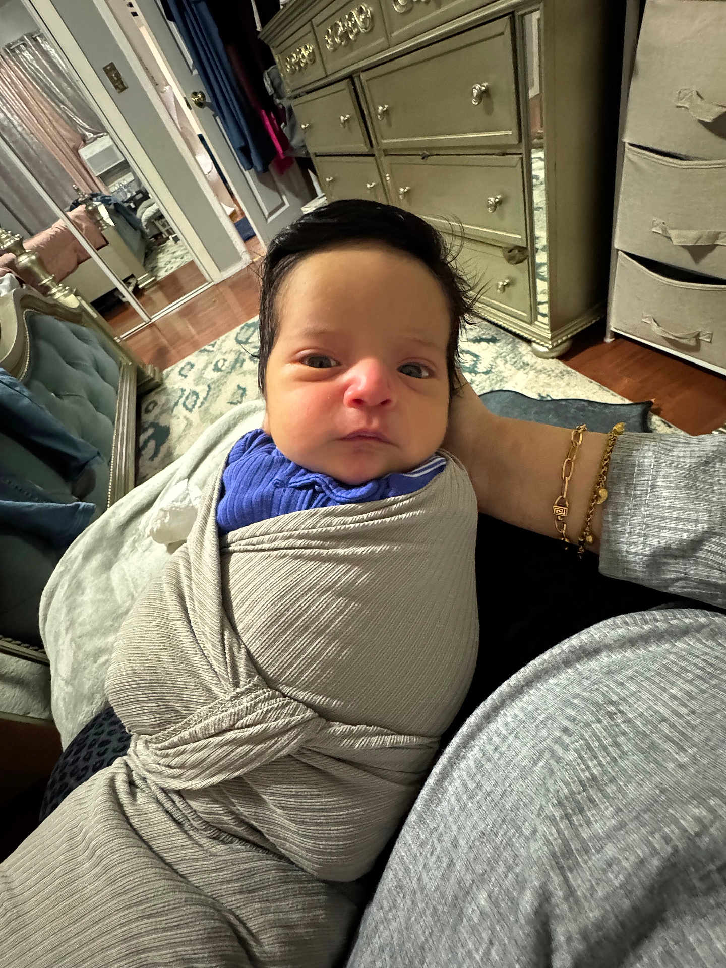 Laith joined the competition — help win amazing prizes! baby, bedroom, bracelet, clothing, dresser, face, floor, furniture, hand, head, indoors, infant, jewelry, mirror, person, portrait, rug, swaddle, wooden_floor, wrapped