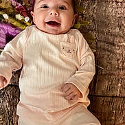 Symphony is registered to the contest to win money with this photo: baby, infant, smiling, happy, onesie, clothing, blanket, floral_pattern, textured_floor, laying_down, portrait, cute, big_eyes, hand, mouth_open, skin, face, cozy, bunny_patch, newborn