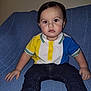Junior is registered to the contest to win money with this photo: toddler, child, boy, polo_shirt, jeans, socks, couch, blue_couch, indoor, portrait, serious_expression, seated, clothing, person, face, young_child, casual_wear, home_interior, cute, looking_at_camera