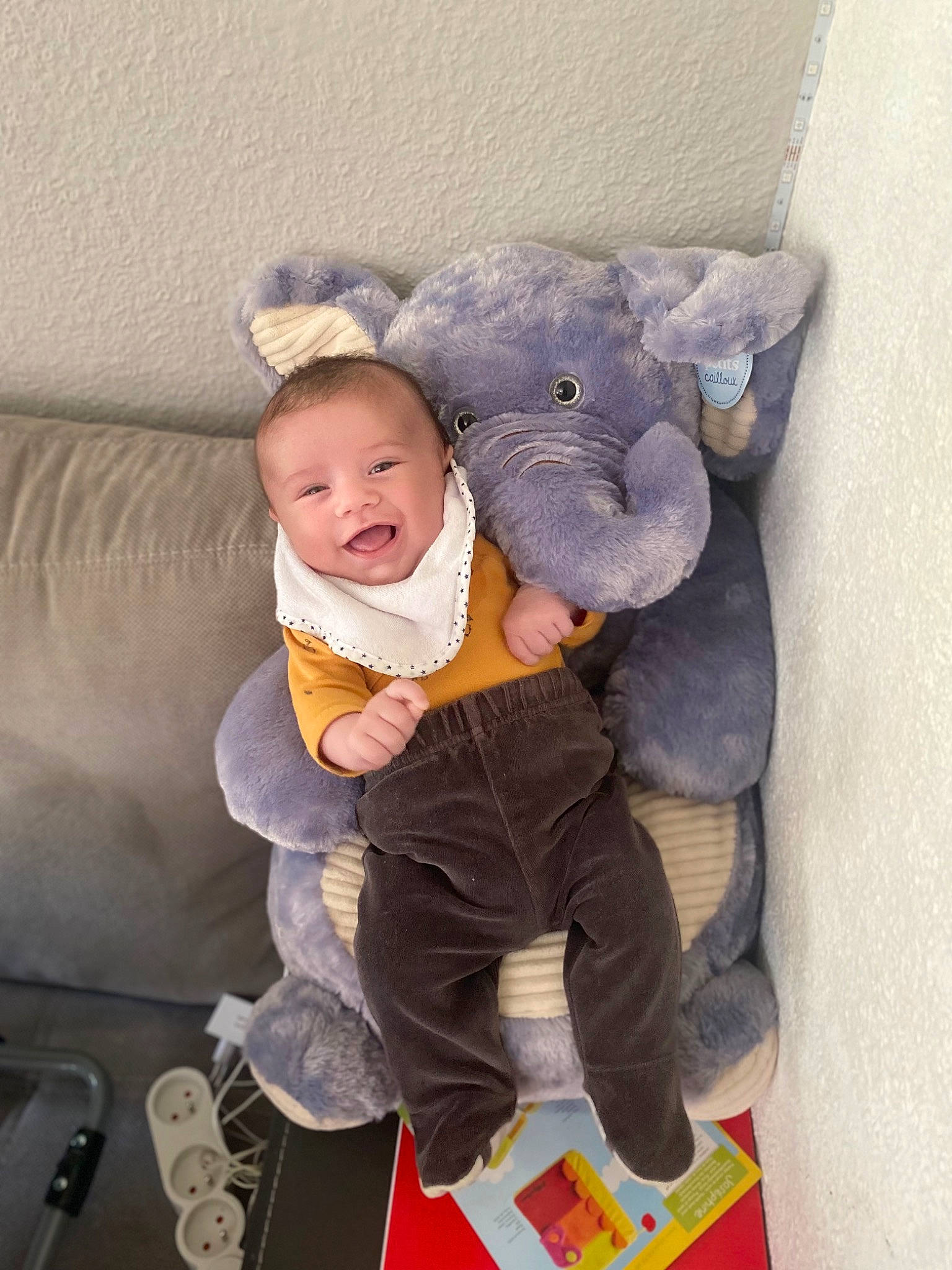 Nathanaël a rejoint le concours — aidez-le/la à gagner de superbes lots ! baby, baby_products, baby_toddler_clothing, cheek, child, comfort, couch, floor, flooring, head, human_body, lap, linens, person, purple, sitting, sleeve, smile, sock, textile