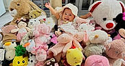 Aliana is registered to the contest to win money with this photo: baby, child, stuffed_animals, plush_toys, teddy_bear, bunny, pink, yellow, white, indoor, smiling, cute, soft_toys, playful, happy, toy_collection, cuddly, colorful, infant, portrait