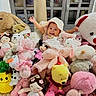 Aliana is registered to the contest to win money with this photo: baby, child, stuffed_animals, plush_toys, teddy_bear, bunny, pink, yellow, white, indoor, smiling, cute, soft_toys, playful, happy, toy_collection, cuddly, colorful, infant, portrait