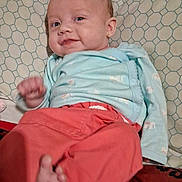 Eleanor joined the competition — help win amazing prizes! baby, infant, smile, red_pants, blue_sweater, lying_down, pillow, patterned_pillow, foot, hand, cute, cheeky, indoors, child, person, cozy, happy, small, young, casual_clothing