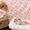 Brynlee joined the competition — help win amazing prizes! baby, newborn, sleeping, bow, knit_sweater, white_cushion, floral_backdrop, pink, woven_basket, vase, dried_pampas_grass, nursery, cozy, indoor, resting, infant, cute, peaceful, child, portrait