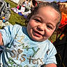toddler, child, smiling, curly_hair, blue_shirt, outdoor, grass, sunny, backyard, fence, person, blanket, bag, playing, happy, casual_clothing, daylight, portrait, closeup, fun