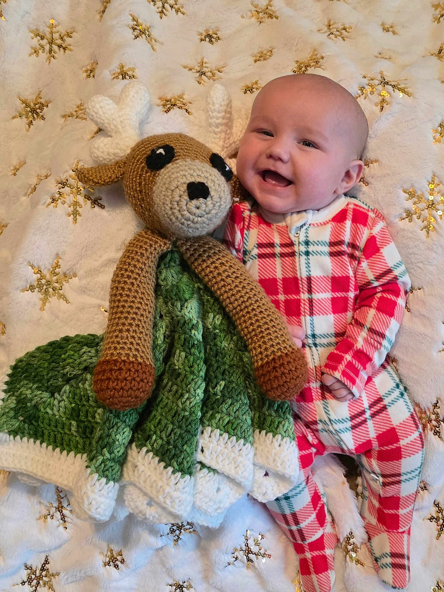 Bentley is registered to the contest to win money with this photo: baby, infant, plaid_onesie, crocheted_toy, reindeer, blanket, snowflake_pattern, smiling, happy, lying_down, cozy, soft_texture, handmade, child, cute, holiday_theme, warm, comfort, toy, portrait