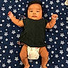 baby, infant, diaper, black_top, star_pattern, blanket, lying_down, cute, indoors, child, skin, foot, hand, face, expression, person, young, apparel, comfort, resting